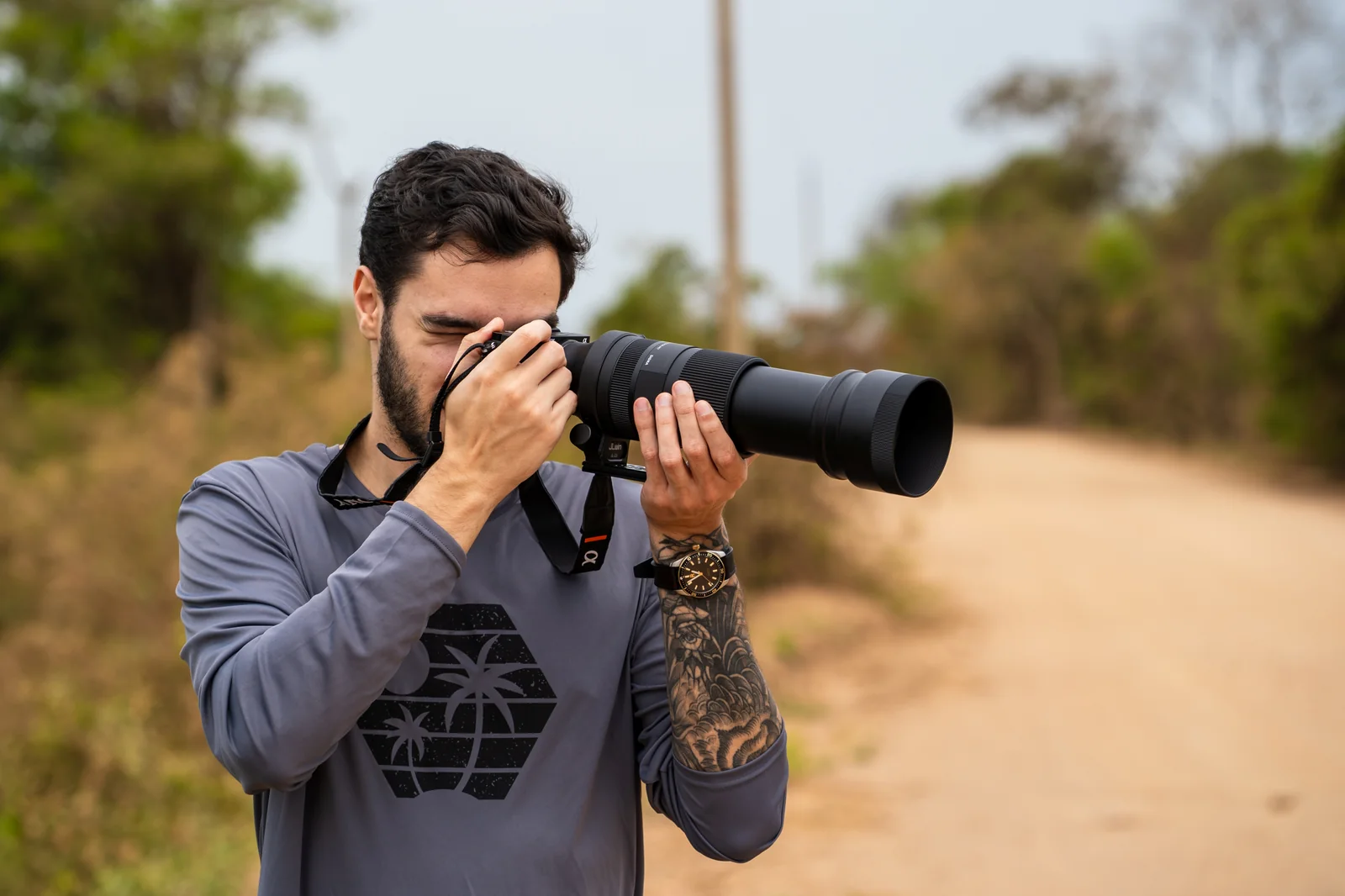Arthur Diaz Bregolin fotografando com uma teleobjetiva em uma estrada de terra no Pantanal