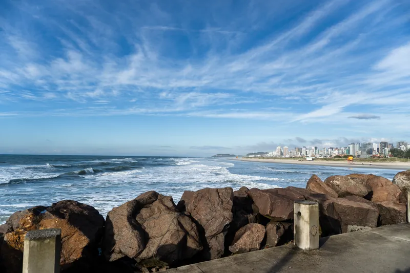 Vista dos Molhes da Barra em Torres (RS), com céu azul e o horizonte da cidade ao fundo