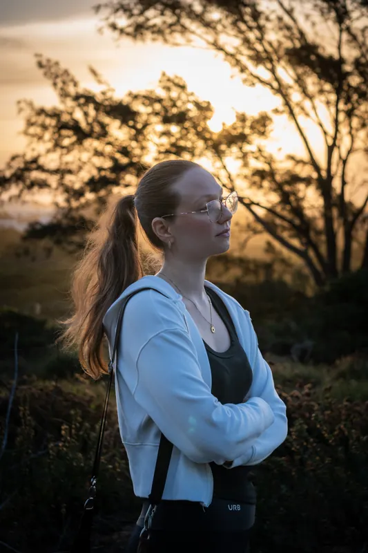Retrato de mulher contra a luz dourada do pôr do sol entre árvores