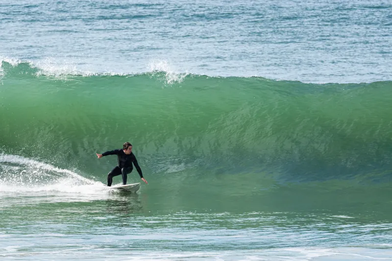 Surfista desliza pela parede verde de uma onda na Rosa do Sul